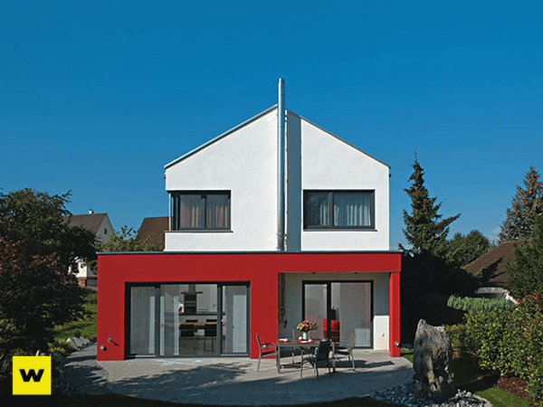 Modernes Einfamilienhaus mit roter Fassade, Flachdach und Terrasse im grünen Garten.